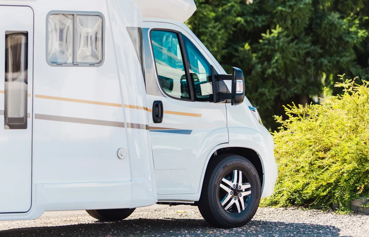 A side view of a white RV parked outdoors